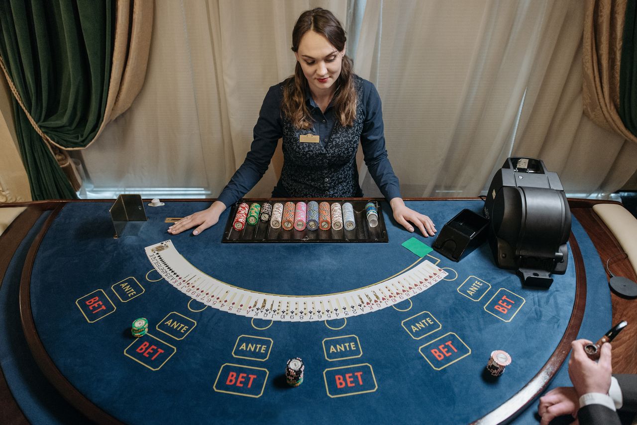 Services Professional female casino dealer managing a gaming table with chips and cards in a luxurious setting.